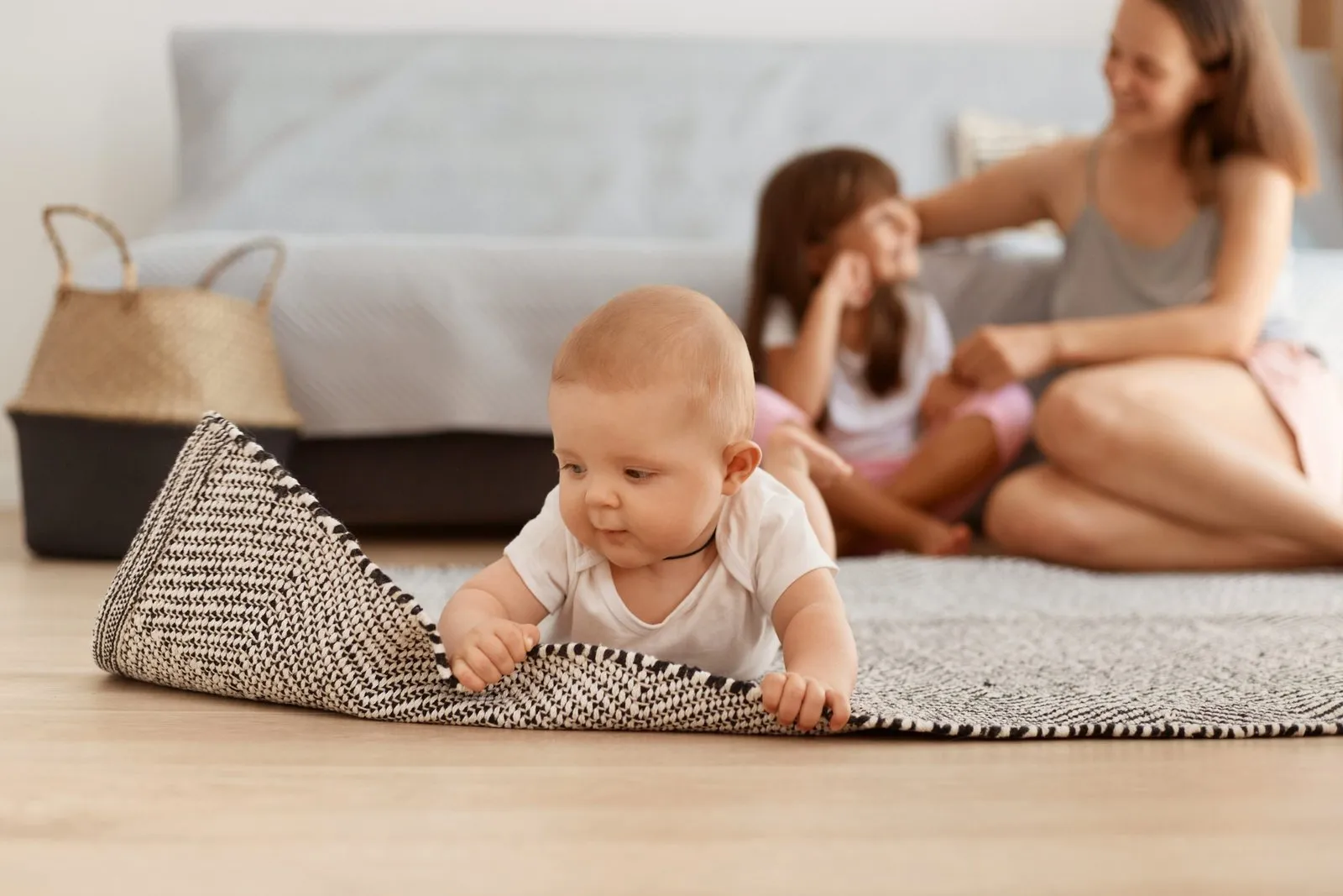 charming-baby-girl-studying-world-around-touching-carpet-while-lying-floor-living-room-adorable-kid-wearing-white-clothing-mother-sister-posing-background-scaled.jpg